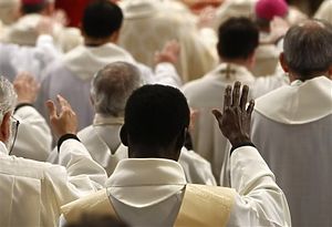 Priests raise their right arm as they follow a Chrism Mass celebrated by Pope Benedict XVI, small figure in the background on the altar, inside St. Peter's Basilica, at the Vatican, Thursday, April 1, 2010. Benedict XVI urged priests to oppose violence as he led a ceremony dedicated to the priesthood Thursday, marking a Holy Week with his church buffeted by clergy sex abuse scandals. The Chrism Mass marks the start of the Easter celebrations. (AP Photo/Pier Paolo Cito)